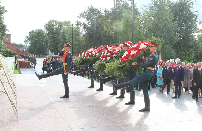 Военнослужащие вынесли три венка из еловых ветвей, красных гвоздик и белых хризантем под звуки военного оркестра