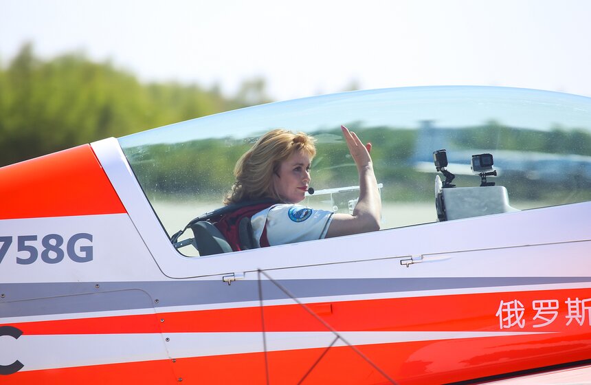 Зрителей приветствует Светлана Капанина − семикратная чемпионка мира по высшему пилотажу, заслуженный мастер спорта и заслуженный тренер России, летчик-инструктор "ОКБ Сухого"