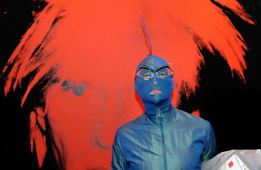 Дизайнер Андрей Бартенев на фоне автопортрета Энди Уорхола на передвижной выставке "Энди Уорхол: художник современной жизни", представленной в Государственной Третьяковской галерее на Крымском валу, 2005 г.