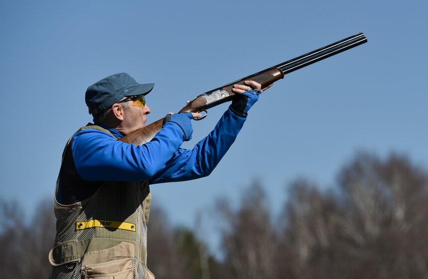 Желтая полоса на жилетке стрелка означает уровень, выше которого не должен находиться приклад ружья до вылета мишени. Правда стреляют навскидку спортсмены только на ските. На трапе стрелок всегда стоит на изготовке.