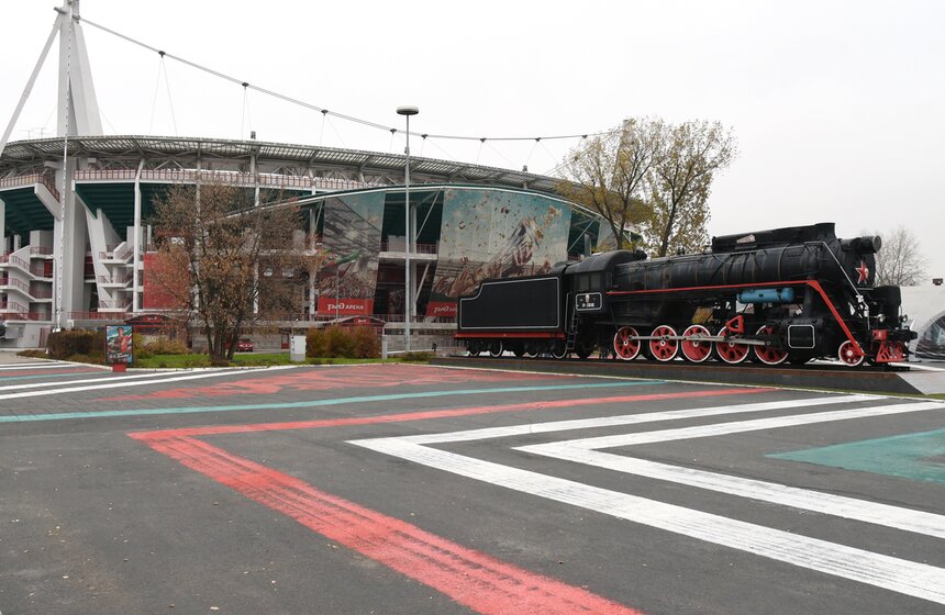 Гигантский арт-объект Покраса Лампаса буквально застелил собой площадь перед стадионом, гармонично дополнив архитектурный ансамбль сооружения, а главное – проход к нему открыт для всех желающих: чтобы увидеть красно-зеленое каллиграфити, билет на матч покупать не нужно