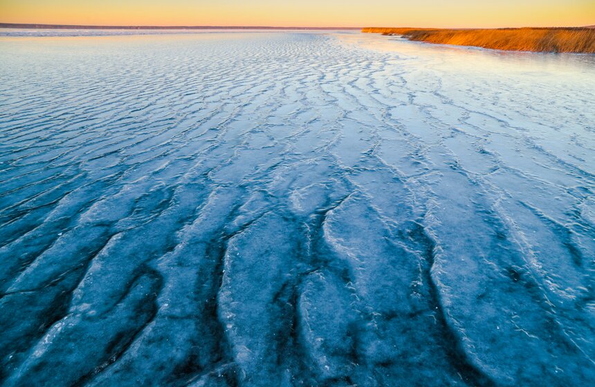 Если в это время дует ветер в одну сторону, то он продолжает нагонять воду на уже замерзшие участки. На поверхности льда формируется рябь и даже небольшие ледяные волны